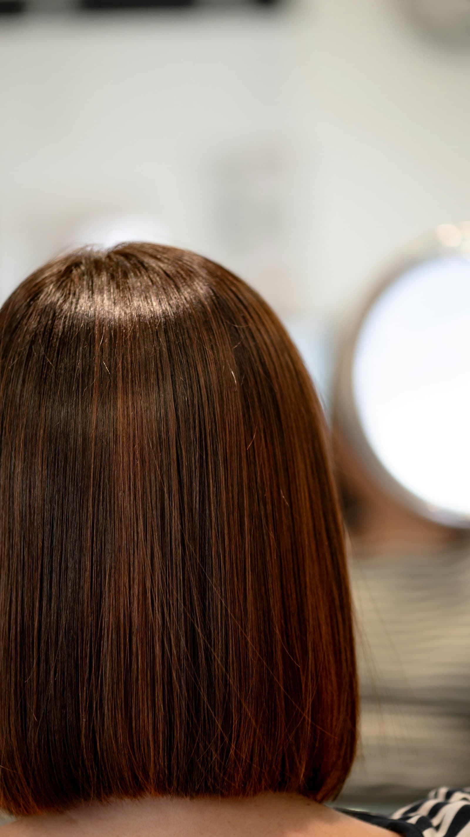 A sleek warm brunette bob photographed from behind in the salon