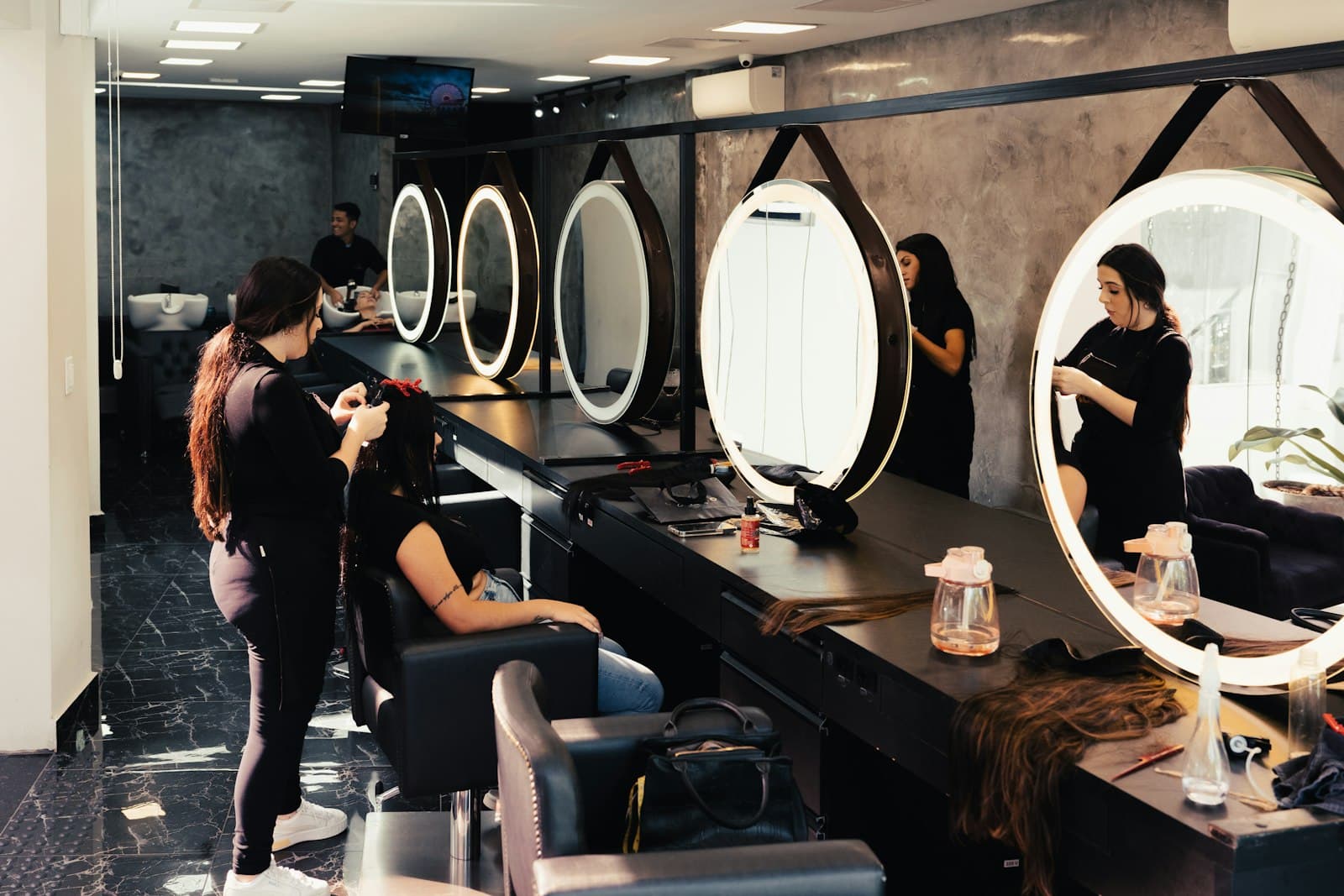 Stylists finishing blow dries at a run of round lit mirrors