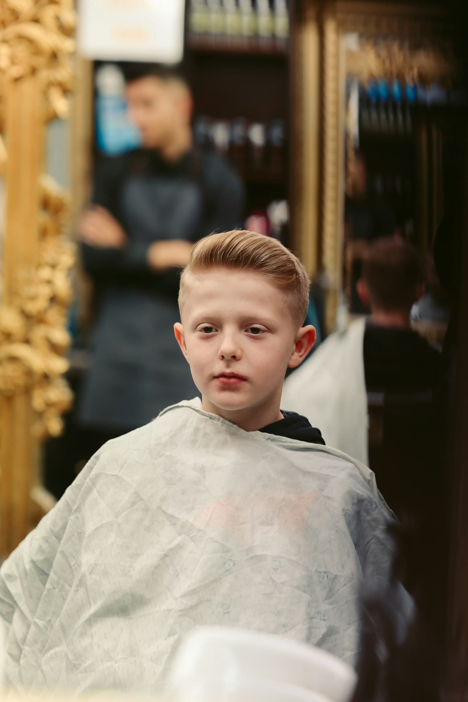 A boy fresh from his cut, gowned in the chair