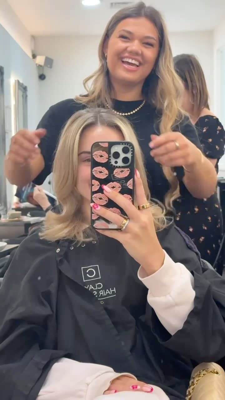 A stylist and client sharing a laugh at the chair, from the Clay Instagram feed