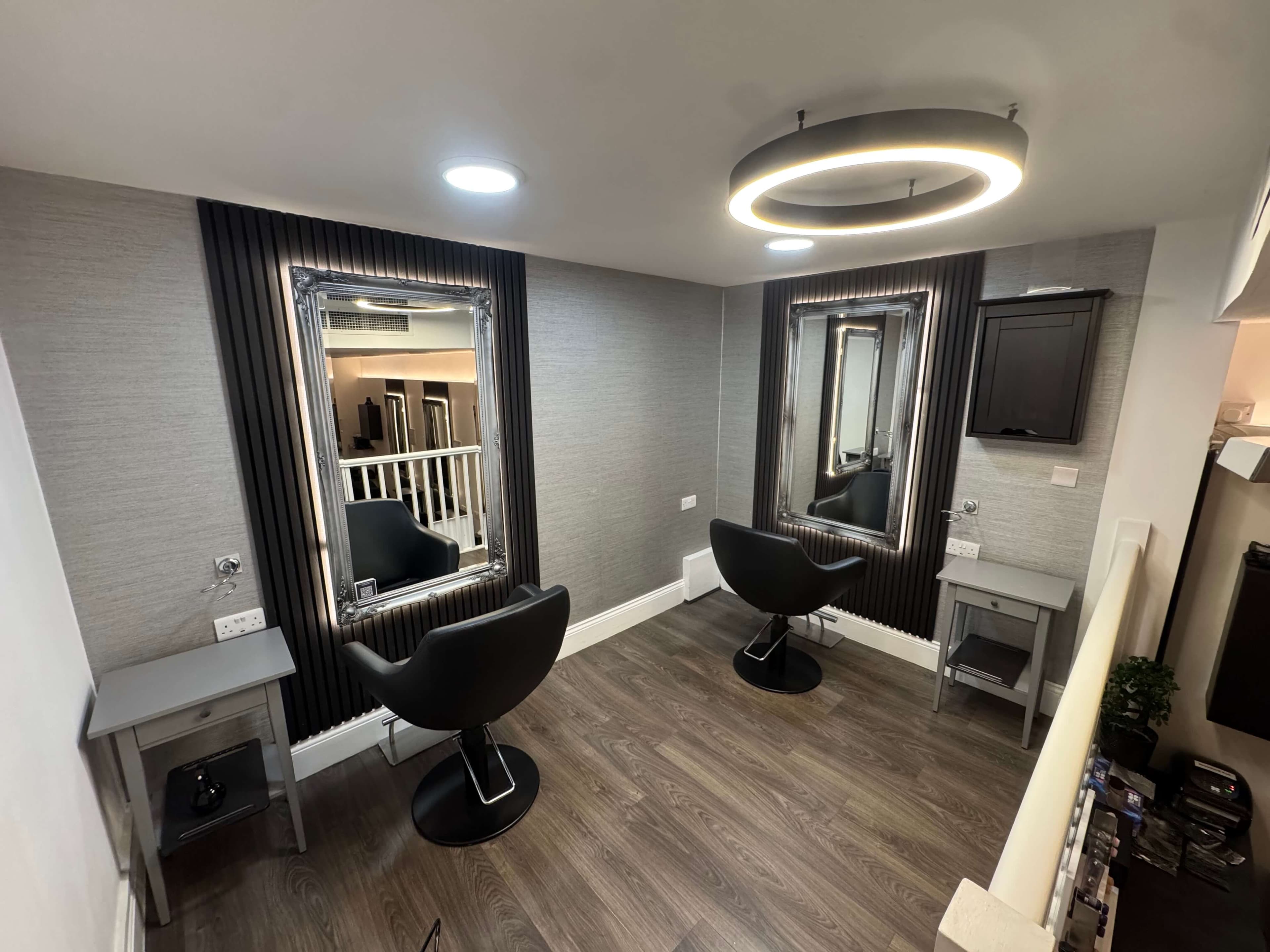 The upstairs styling room at Clay, framed mirrors and a halo light overhead